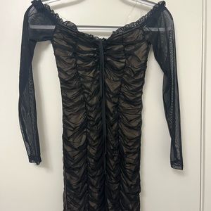Women’s black ruched mini dress with sheer long sleeves.